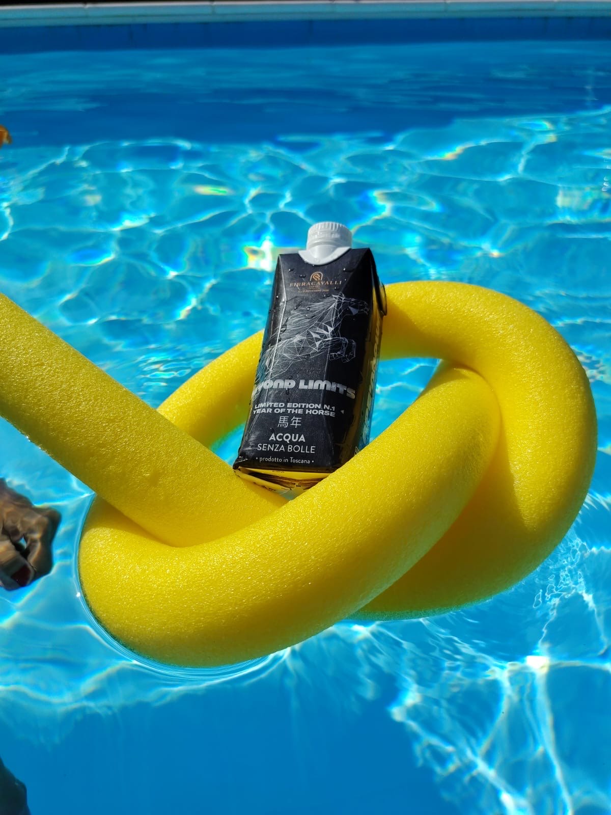 Brick di acqua Beyond Limits appoggiato su un tubo galleggiante giallo in piscina