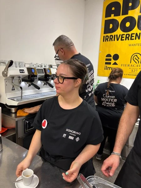 Una ragazza del team Ape'n Down prepara il caffè alla macchina durante Vinitaly 2025