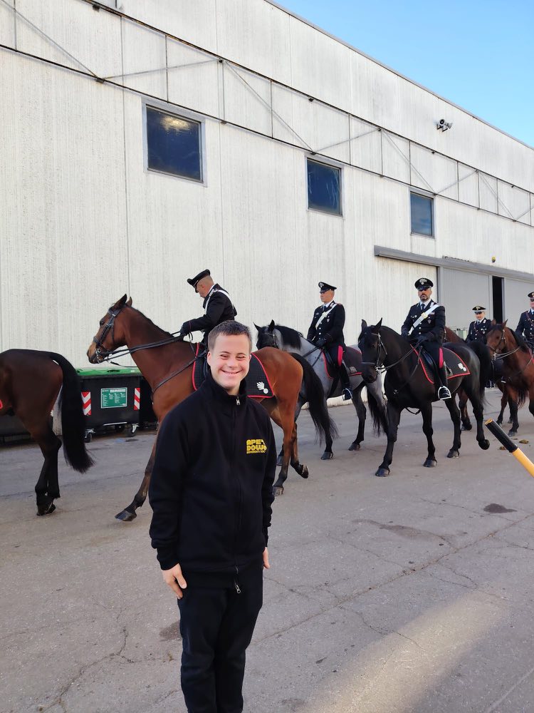 Un ragazzo Ape'n Down sorride davanti ai carabinieri a cavallo, all'esterno dei padiglioni di Fieracavalli